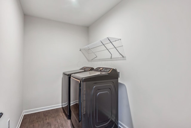 clothes washing area featuring laundry area, wood finished floors, independent washer and dryer, and baseboards