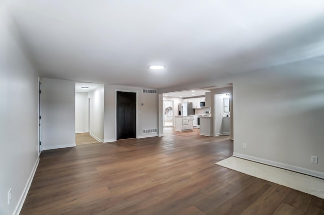 unfurnished living room featuring visible vents, dark wood finished floors, and baseboards