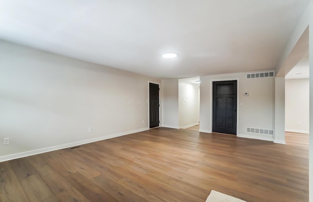 empty room featuring wood finished floors, visible vents, and baseboards