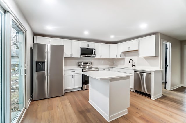 kitchen with stainless steel appliances, light wood-type flooring, a sink, and light countertops