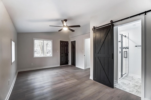 spare room with lofted ceiling, ceiling fan, a barn door, and wood finished floors