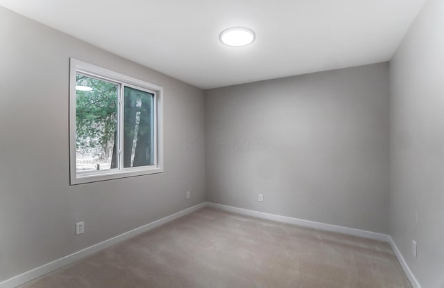 empty room featuring light colored carpet and baseboards