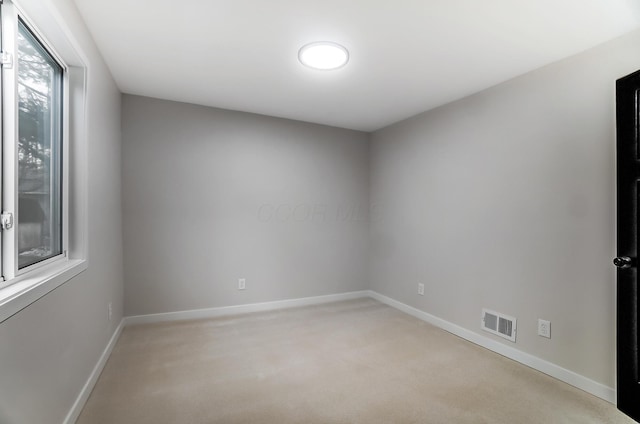 spare room with light carpet, visible vents, and baseboards