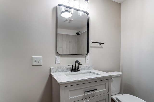 bathroom with toilet, visible vents, and vanity