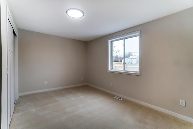 unfurnished bedroom with light carpet, a closet, visible vents, and baseboards