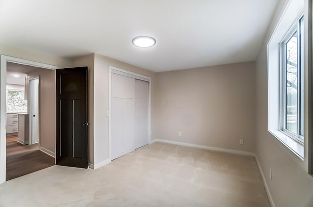 unfurnished bedroom featuring carpet floors, a closet, and baseboards