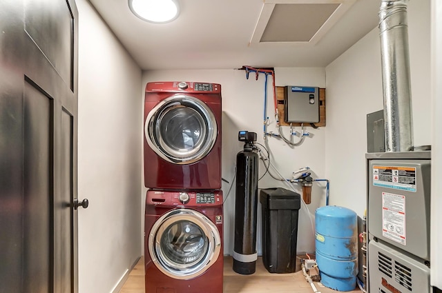 clothes washing area featuring stacked washer and dryer, attic access, laundry area, and wood finished floors