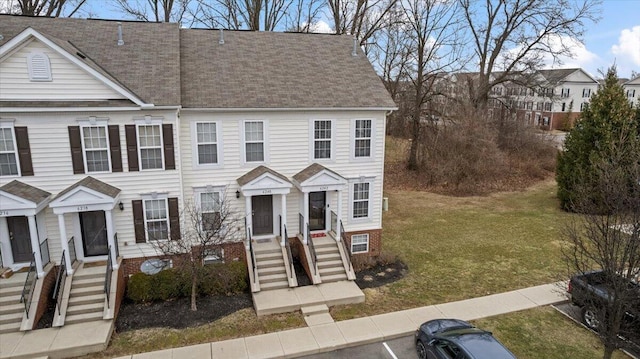 townhome / multi-family property with a front lawn and a shingled roof