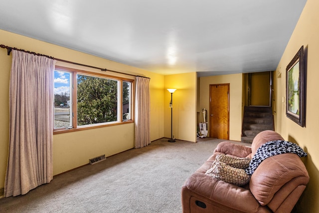 carpeted living area featuring visible vents and stairway