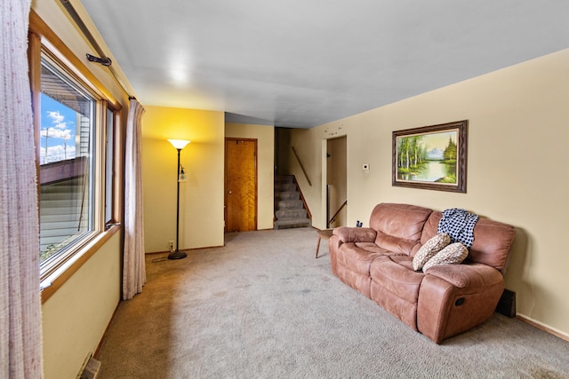 carpeted living area featuring stairs