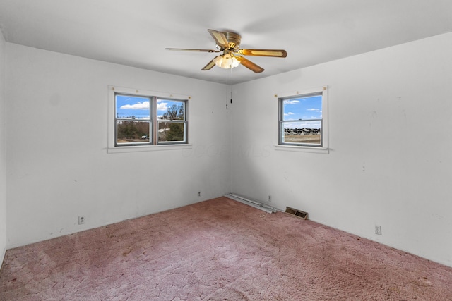 carpeted empty room featuring a ceiling fan, a wealth of natural light, and visible vents