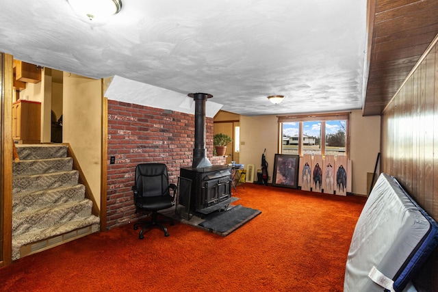 unfurnished living room with a wood stove, stairs, and carpet floors