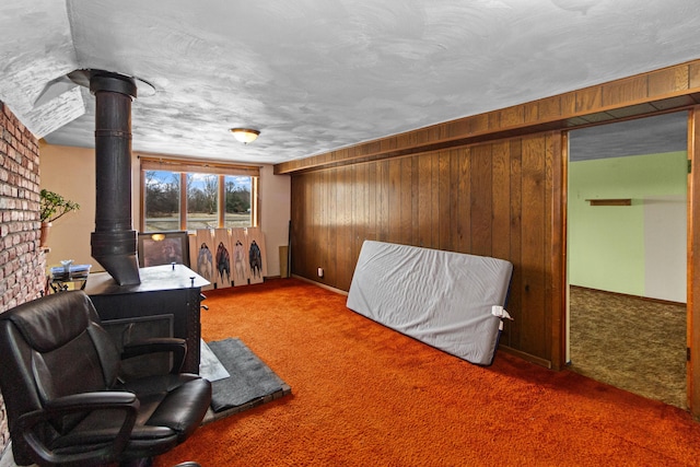 carpeted bedroom featuring a wood stove, wood walls, and a textured ceiling