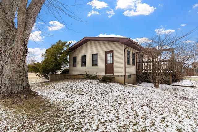 snow covered property with entry steps and a wooden deck