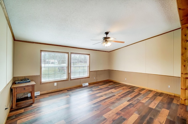 spare room with a wainscoted wall, crown molding, a textured ceiling, and wood finished floors