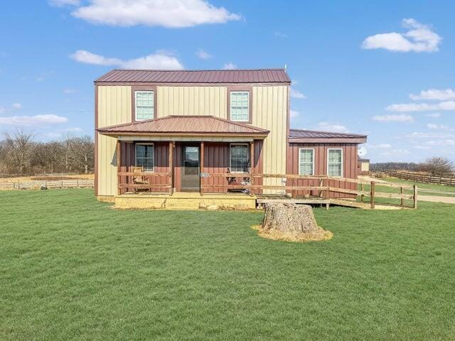 view of front facade featuring a front lawn, metal roof, and board and batten siding