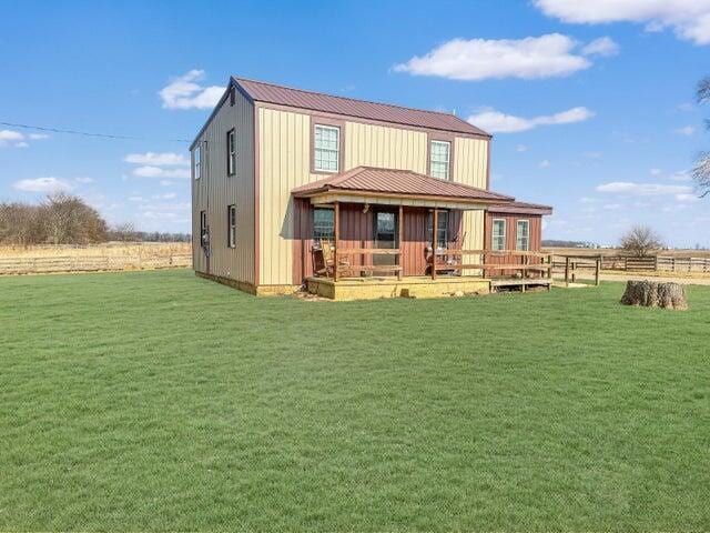 back of house featuring a rural view, metal roof, and a yard