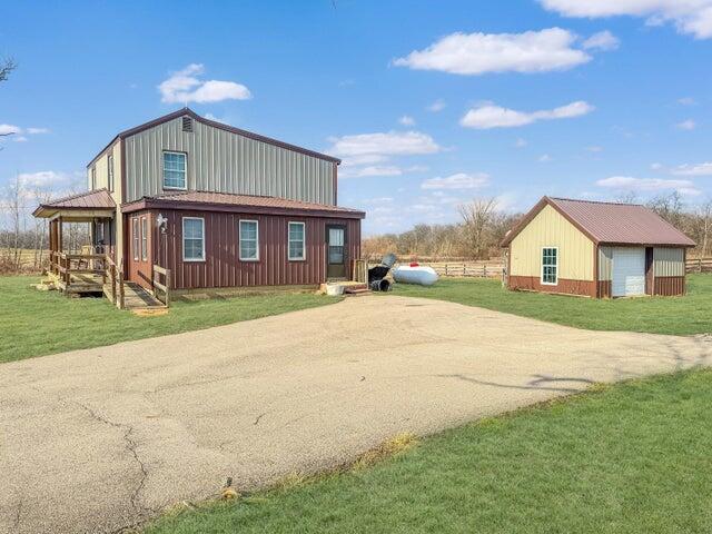 view of property exterior with an outbuilding, a garage, fence, driveway, and a lawn