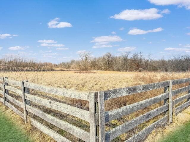 view of yard with fence and a rural view
