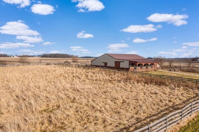 view of yard featuring an outbuilding, a rural view, and fence