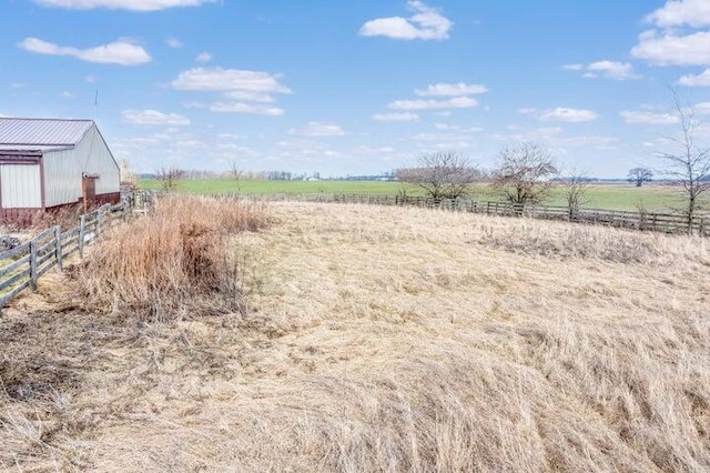 view of yard with an outbuilding, a rural view, and fence