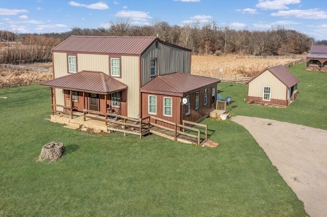 view of front of property with driveway, metal roof, and a front lawn