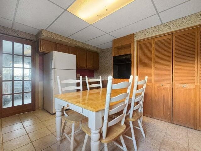 dining space featuring a wealth of natural light, a paneled ceiling, and wallpapered walls
