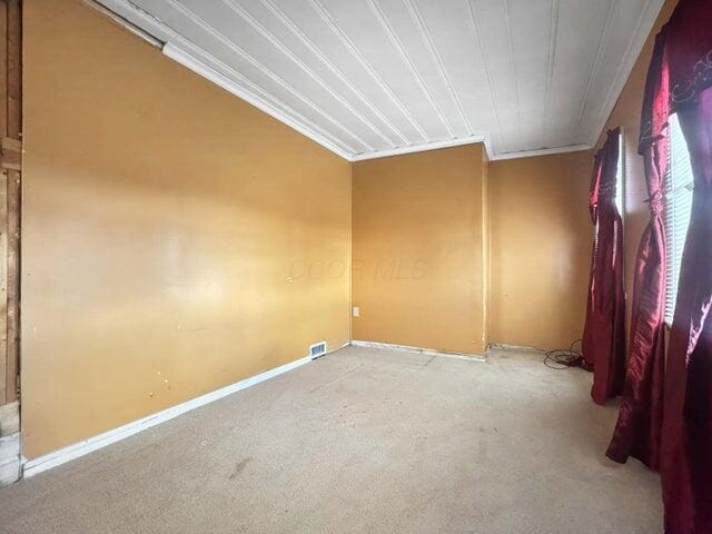 carpeted spare room featuring ornamental molding and baseboards