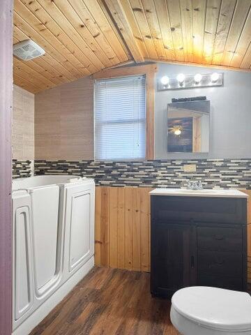 interior space featuring lofted ceiling, wood ceiling, backsplash, and dark wood-style flooring