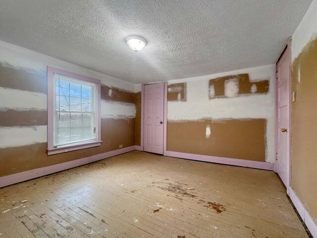 empty room with a textured ceiling, baseboards, and hardwood / wood-style flooring