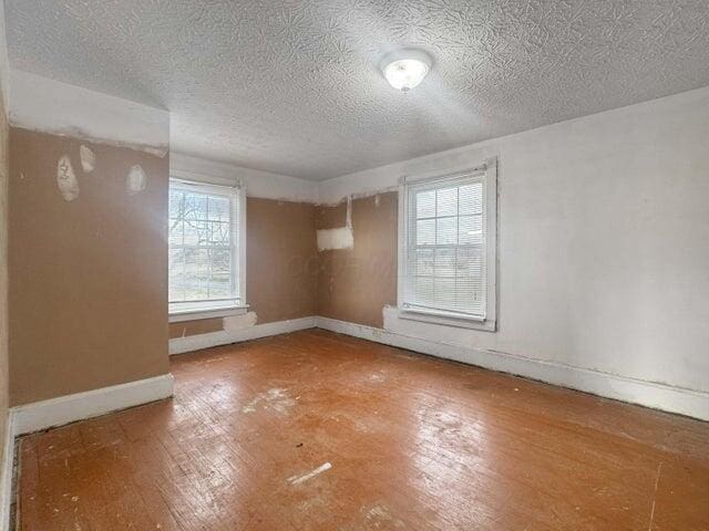 spare room with hardwood / wood-style flooring, a wealth of natural light, and baseboards