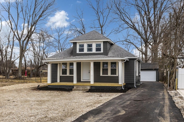 view of front of house featuring an outbuilding, a porch, a shingled roof, a garage, and driveway