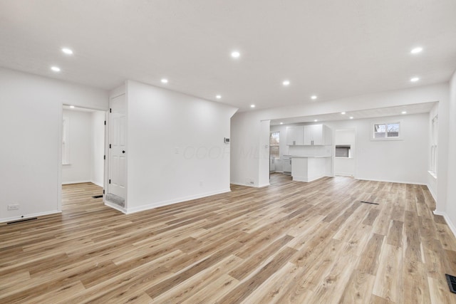 unfurnished living room with baseboards, light wood-type flooring, visible vents, and recessed lighting