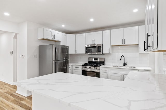 kitchen with light stone countertops, appliances with stainless steel finishes, decorative backsplash, and a sink