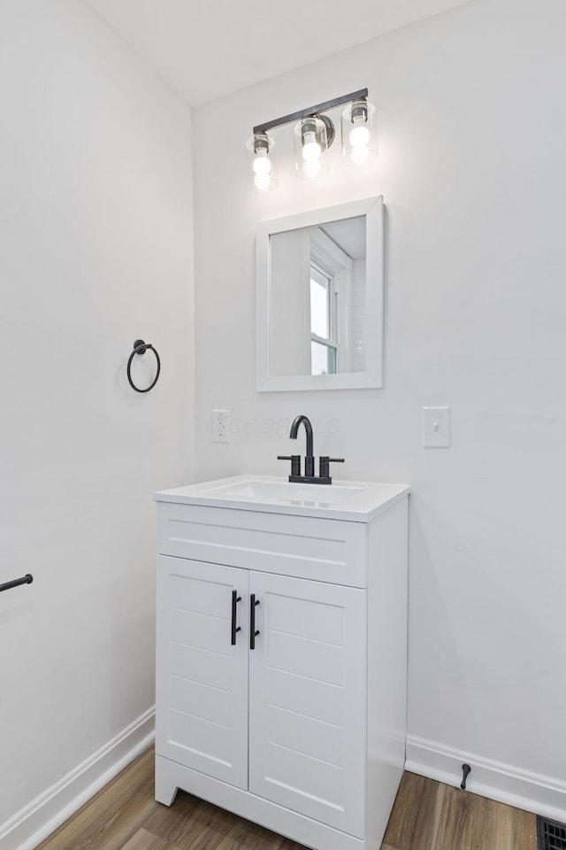 bathroom with wood finished floors, vanity, and baseboards