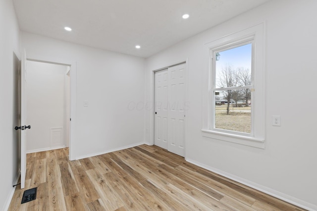 empty room featuring light wood finished floors, visible vents, and a wealth of natural light