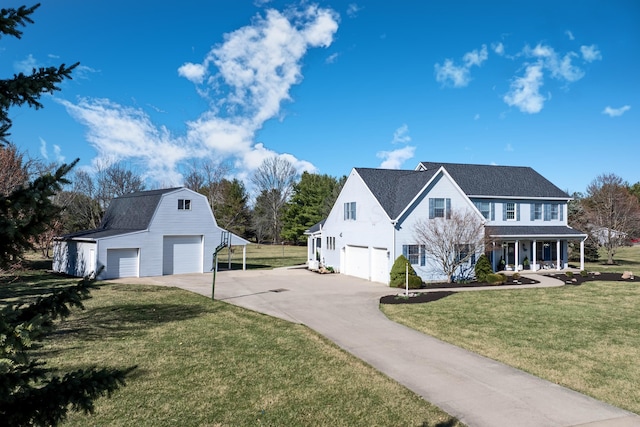 view of home's exterior featuring a gambrel roof, covered porch, a yard, an outbuilding, and driveway