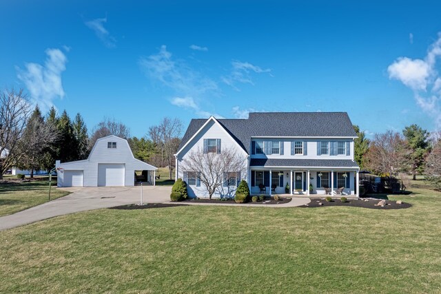 colonial inspired home with a porch, an outdoor structure, a garage, and a front yard