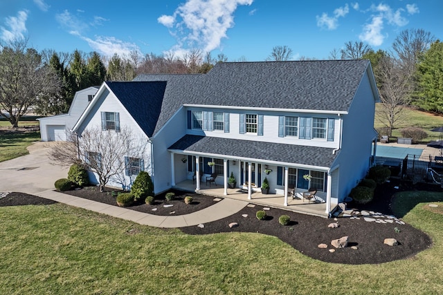 traditional home with a garage, covered porch, a shingled roof, and a front lawn