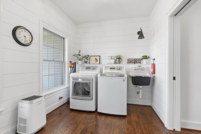 clothes washing area with washer and dryer, a sink, dark wood finished floors, baseboards, and laundry area