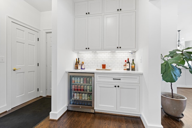 bar featuring beverage cooler, backsplash, dark wood finished floors, baseboards, and a dry bar