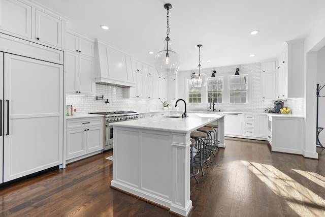 kitchen featuring a sink, custom exhaust hood, stainless steel range, white cabinetry, and dark wood-style flooring