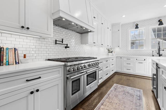 kitchen with premium range hood, dark wood finished floors, white cabinets, light countertops, and range with two ovens