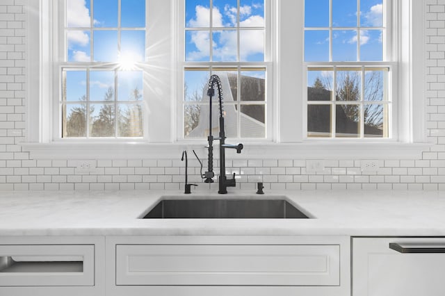 details with a sink, tasteful backsplash, and white cabinets