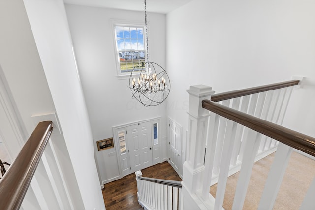 stairway featuring wood finished floors and a chandelier