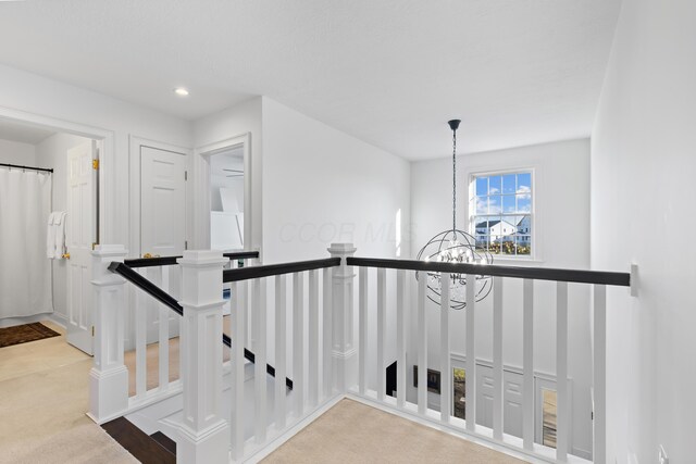 hall with an upstairs landing, a notable chandelier, carpet flooring, and recessed lighting