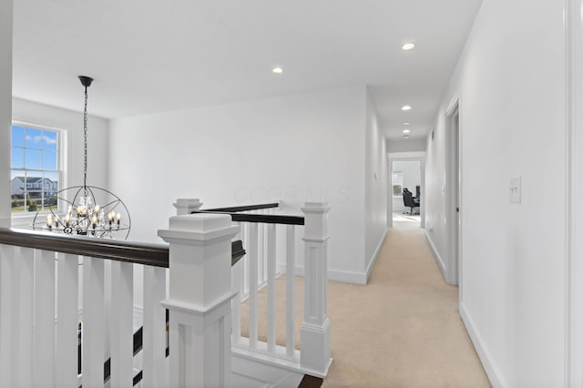 hallway featuring baseboards, an inviting chandelier, recessed lighting, light carpet, and an upstairs landing