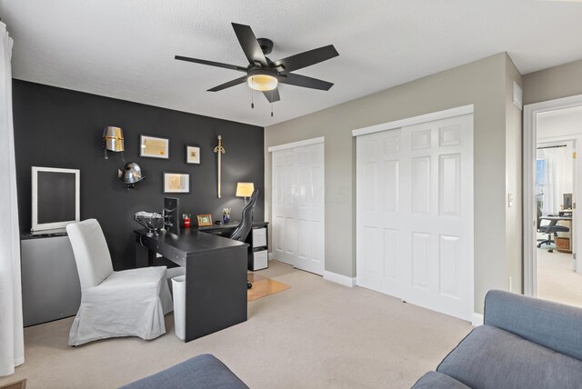 office area featuring a ceiling fan, light colored carpet, and baseboards