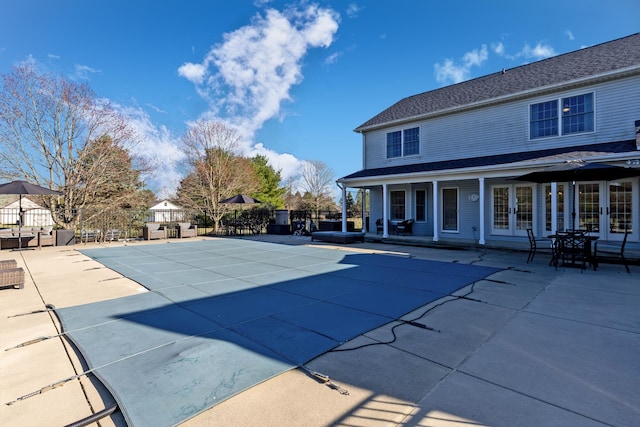 view of pool with a patio area, french doors, and fence