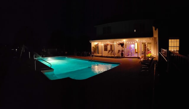 pool at night featuring an outdoor pool and a patio